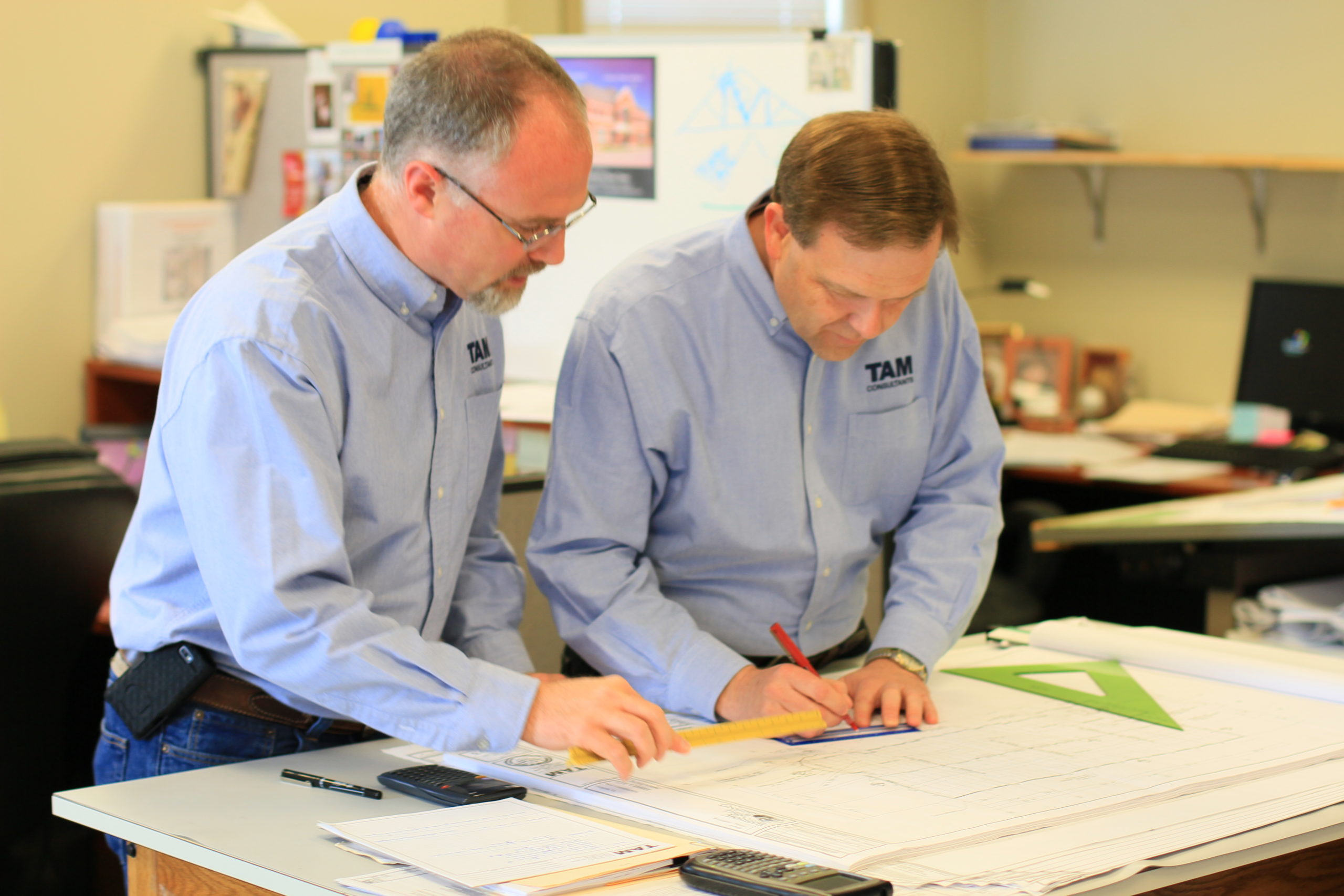 Two TAM Consultants Engineers working on building drawings together