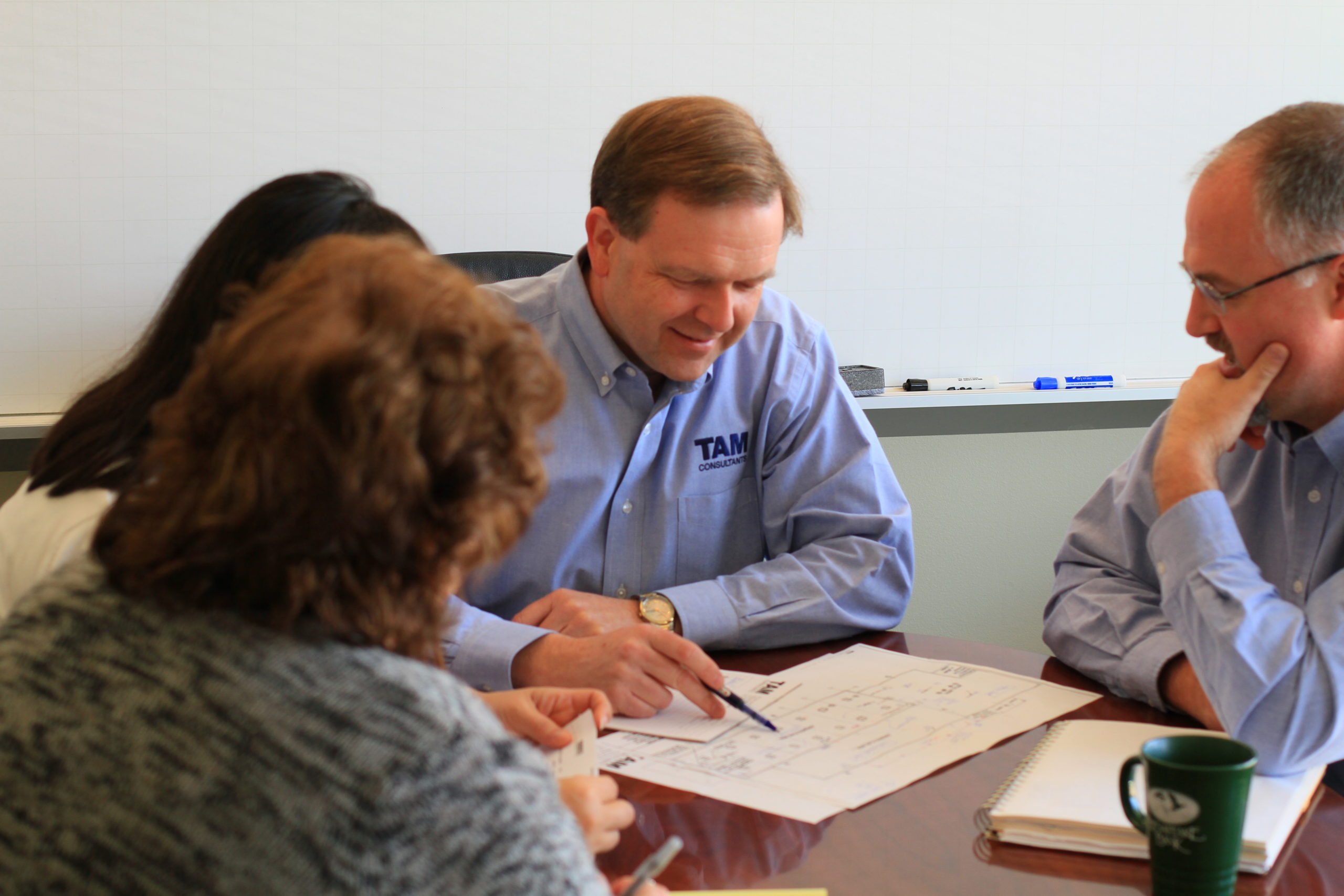 TAM Consultants Employees having a discussion while gathered around a conference table 